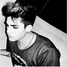 a black and white photo of a young man wearing a t-shirt and earring .