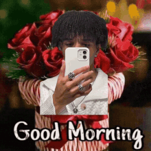 a man is taking a picture of himself in front of a bouquet of red roses and says good morning