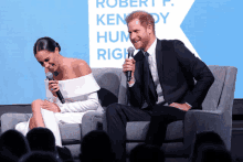 prince harry and meghan markle are sitting on a couch and laughing