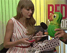 a woman in a white and red dress is holding a green parrot in front of a sign that says red on it