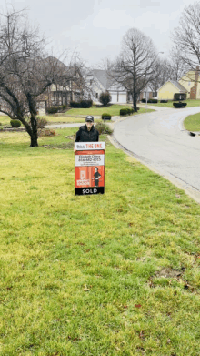 a man holding a sold sign in a grassy area