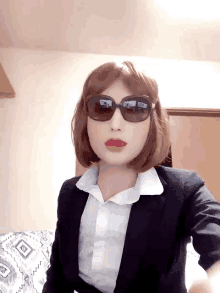 a woman wearing sunglasses and a suit has a reflection of her face in the sunglasses