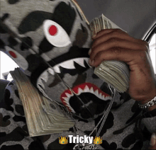 a picture of a person holding a stack of money with tricky written on it