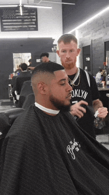 a man in a brooklyn shirt is getting his hair cut