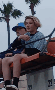 two young boys are riding a roller coaster with the number 22 on the side of the box