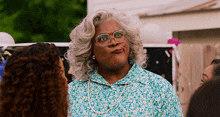 a woman wearing glasses and a floral shirt is talking to a group of women