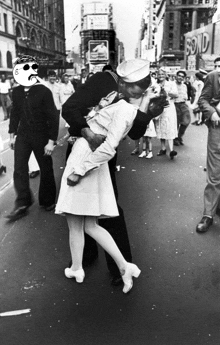 a black and white photo of a man kissing a woman on the street