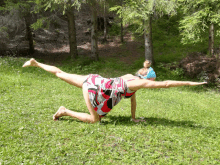 a woman in a red and black dress is doing a yoga pose