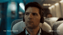 a man wearing headphones on an airplane with the twilight zone on the bottom right