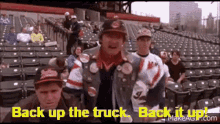 a group of people are standing in a stadium with the words `` back up the truck , back it up '' written on the screen .