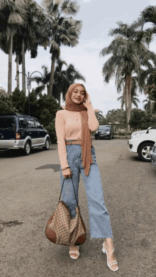 a woman wearing a hijab is standing on a street holding a gucci bag