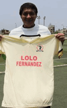 a man is holding a white shirt that says lolo fernandez on it .