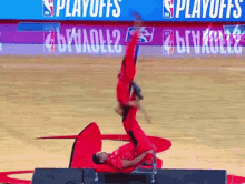 a man is doing a handstand on a basketball court in front of a sign that says " playoffs "