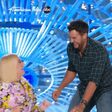 a man and a woman are dancing on a stage in front of a sign that says american idol abc