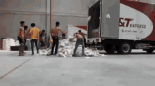 a group of men are standing around a large pile of paper in front of a st express truck .