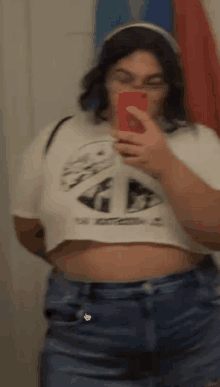 a woman is taking a selfie in front of a mirror while wearing a crop top .