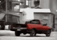 a red truck is driving down a street with a large object in the back of it .