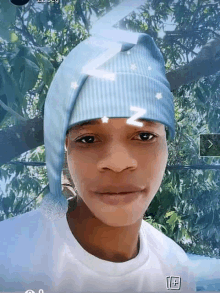 a young man wearing a blue hat and a white shirt is looking at the camera .