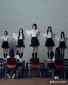 a group of girls with white wings are standing in a classroom