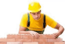 a construction worker is laying bricks on a wall .