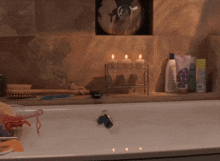 a bathtub in a bathroom with candles and a cd on the wall above it