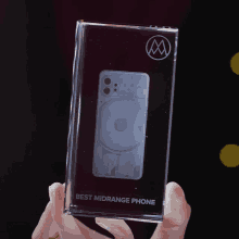 a person is holding a glass block that says best midrange phone on it