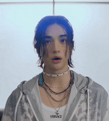 a young man wearing a versace necklace and a choker