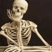 a skeleton is sitting on a table with a ball in his hand .