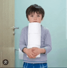 a young boy is holding a roll of toilet paper .