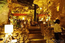 a restaurant in a cave with tables and chairs and a waiter .