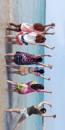 a group of women are standing on a beach with their arms in the air