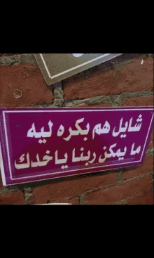 a sign on a brick wall has arabic writing