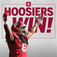 a football player with his arms in the air in front of a poster that says hoosier win