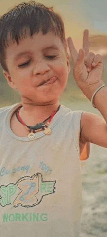 a young boy wearing a shirt that says ' working ' on it is making a funny face .