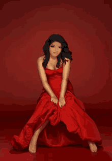 a woman in a red dress sits on a red background