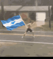 a man is running down a street while holding a blue and white flag with the letter a on it