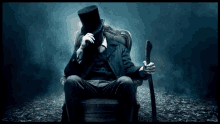 a man wearing a top hat and holding a cane sits in a chair