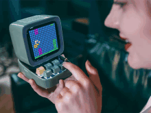 a woman is playing a video game on a small device that looks like a tetris game