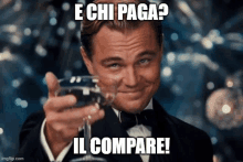 a man in a tuxedo is holding a glass of wine with the caption " e chi paga "