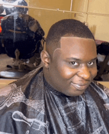 a man wearing a black cape is smiling while getting his hair cut at a barber shop