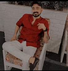 a man in a red shirt sits in a chair