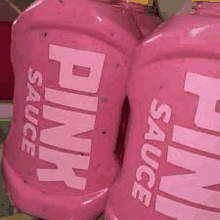 two bottles of pink sauce are sitting on top of each other .