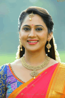 a woman wearing a necklace and earrings smiles at the camera