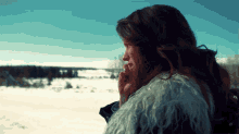 a woman in a fur coat looks out over a snowy landscape