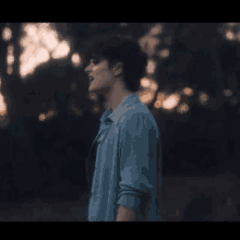 a young man in a blue shirt is standing in a field .