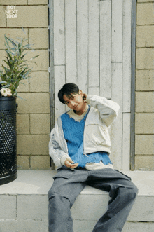 a young man sits on a ledge with a sign that says boy next door on it