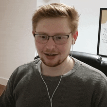 a man wearing glasses and ear buds is smiling in front of a white board that says ' a ' on it