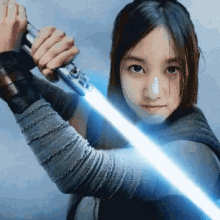 a woman is holding a light saber in her hand .