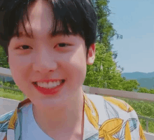 a young boy is smiling for the camera while wearing a yellow and white shirt .