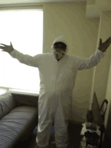 a man in a white protective suit with his arms outstretched in front of a window